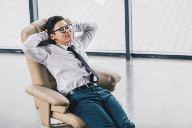 high angle view of young asian businessman in eyeglasses resting in chair  clipart
