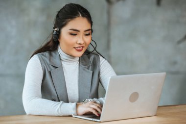 güzel gülümseyen kazak işkadını kulaklık dizüstü Office ile çalışma