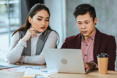 dizüstü bilgisayar ve ofis gazetede çalışan genç Asya iş adamları