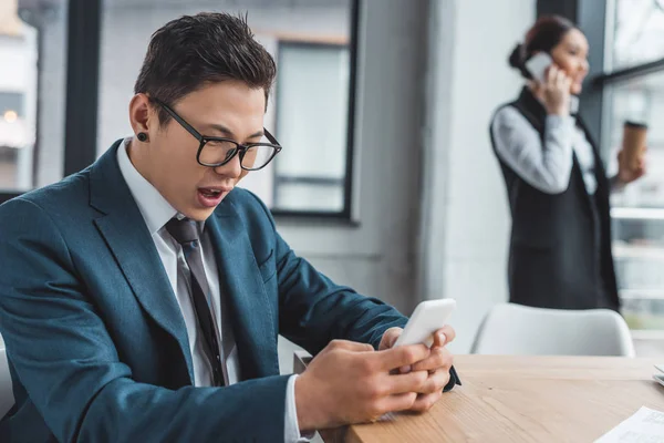 Emotional Young Asian Businessman Using Smartphone Female Colleague Talking Office — Stock Photo, Image