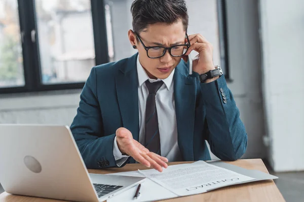 Joven Empresario Concentrado Hablando Por Teléfono Inteligente Mirando Contrato Oficina — Foto de Stock