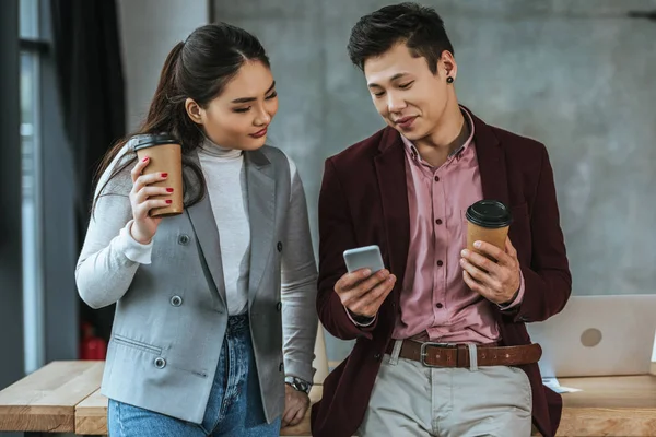 Счастливые Молодые Азиатские Коллеги Бизнесу Держат Кофе Пойти Использовать Смартфон — стоковое фото