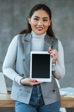 Dijital tablet boş ekran ile tutarak ve kamera Office gülümseyen genç Asya iş kadını