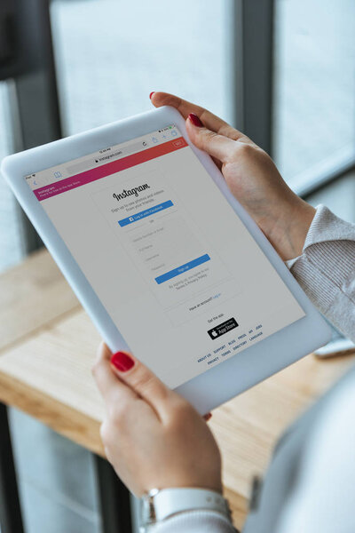 обрезанный снимок бизнесвумен с помощью цифрового планшета с приложением Instagram на экране
