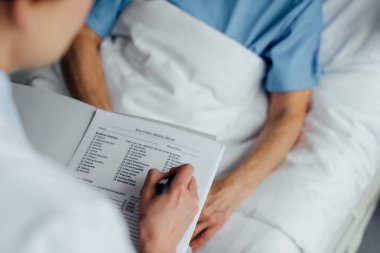 cropped view of doctor holding diagnosis and consulting woman lying in hospital bed  clipart