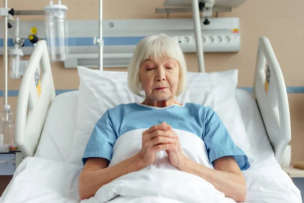 Senior Woman Lying Bed Folded Hands Praying Hospital — Stock Photo, Image