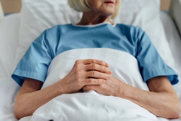 Vista Cortada Mulher Idosa Com Mãos Dobradas Deitada Cama Hospital — Fotografia de Stock