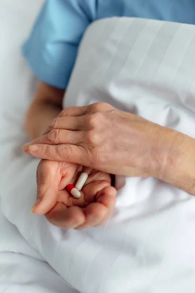 Vista Recortada Mujer Mayor Acostada Cama Sosteniendo Pastillas Hospital —  Fotos de Stock