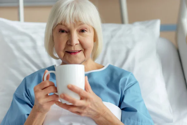 Tersenyum Wanita Senior Berbaring Tempat Tidur Melihat Kamera Dan Minum — Stok Foto