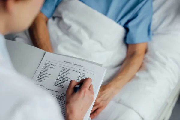 医生拿着诊断和咨询妇女躺在病床上的裁剪视图 — 图库照片