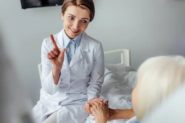 Hermosa Sonriente Doctora Señalando Con Dedo Tomándose Mano Con Mujer — Foto de Stock