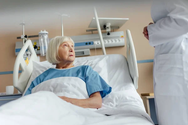 Arzt Berät Verärgerte Seniorin Die Krankenhausbett Liegt — Stockfoto