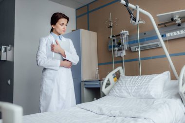 üzgün kadın doktor hastane koğuşunda boş yatak bakarak tanı ile
