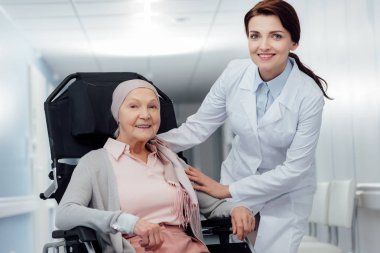 atkı kanserli hastanede tekerlekli sandalyede oturan kadın kıdemli yakınındaki güzel mutlu kadın doktor