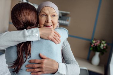 gülümseyen kıdemli kadın fular kucaklama kız hastanede