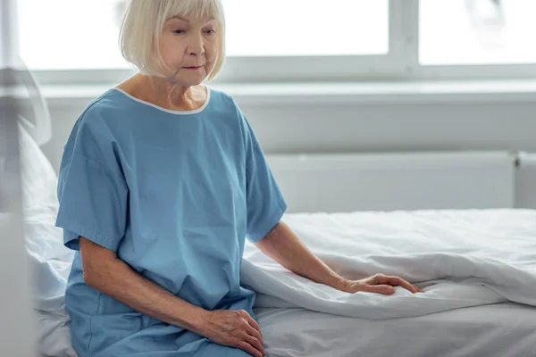 孤独的老年妇女坐在病床上的病房 — 图库照片