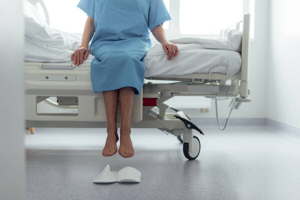 cropped view of senior woman sitting on bed in hospital ward 