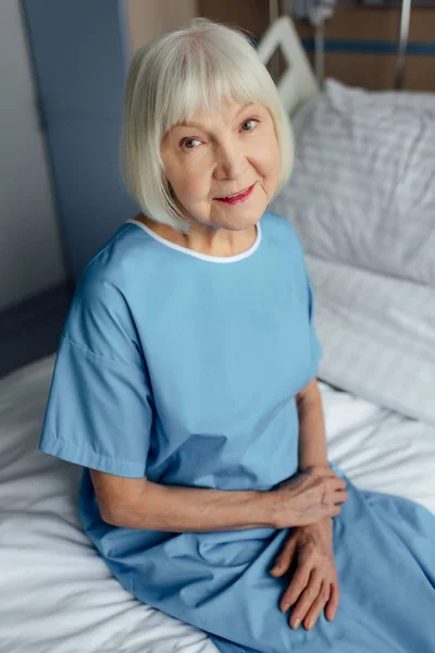 Mujer Mayor Sonriente Con Las Manos Dobladas Sentadas Cama Mirando — Foto de Stock