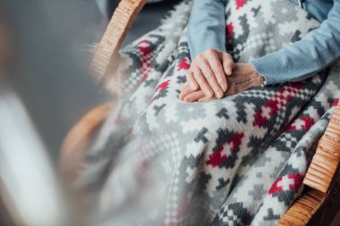 Hasır sallanan sandalye ile battaniye ve katlanmış elleri evde oturan kadın kıdemli görünümünü kırpılmış