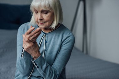 Yatağın üstüne oturan ve evde el ile Nabız ölçme kadın kıdemli