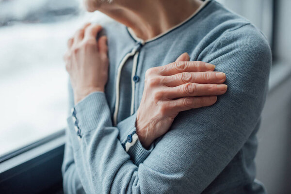 cropped view of senior woman with hands crossed at home 