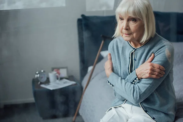 Samotny Senior Kobieta Siedzi Łóżku Rękami Skrzyżowanymi Domu — Zdjęcie stockowe