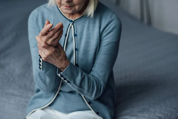 Частичный Вид Пожилой Женщины Сидящей Кровати Измеряющей Пульс Рукой Дома — стоковое фото