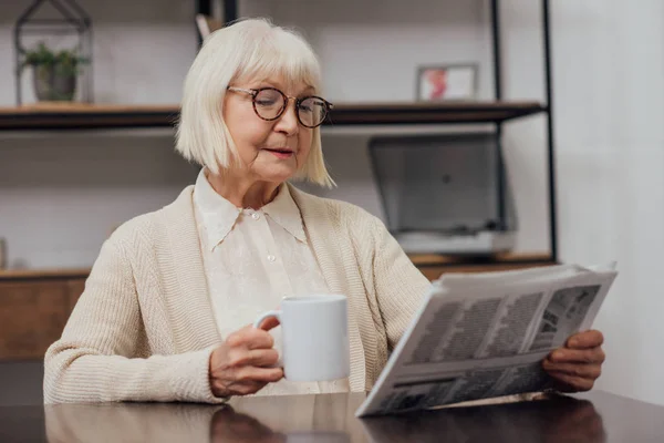 Idősebb Szürke Haj Asztalnál Olvasó Újság Miközben Kávéfogyasztás Otthon — Stock Fotó