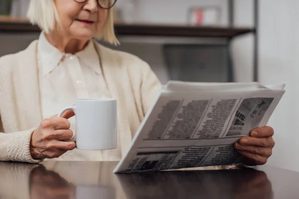 Обрезанный Вид Пожилой Женщины Сидящей Столом Читающей Газету Пьющей Кофе — стоковое фото