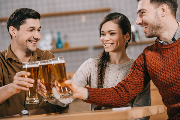 happy group of friends smiling while clinking with beer 