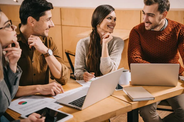 Grupo Sonriente Compañeros Trabajo Hablando Cafetería Cerca Computadoras Portátiles — Foto de Stock