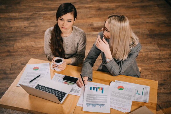 Вид привлекательных коллег, работающих в кафе рядом с ноутбуком
  