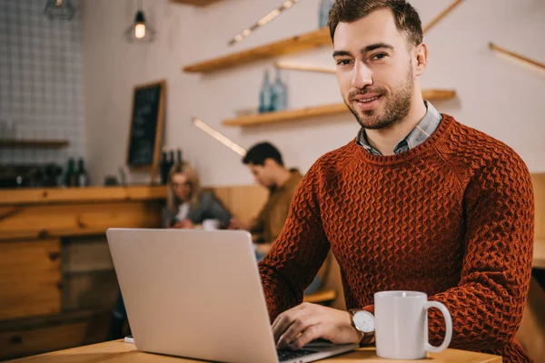 Schöner Mann Schaut Kamera Während Laptop Café Benutzt — Stockfoto