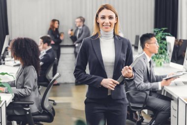 belgeler klasörüyle tutarak ve kamera Office gülümseyen çekici genç iş kadını 