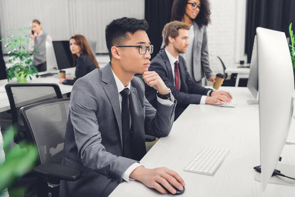 side view of focused businesspeople using desktop computers in office