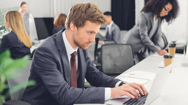 Geconcentreerde Jonge Zakenman Laptop Gebruikt Terwijl Werkt Een Open Ruimte — Stockfoto