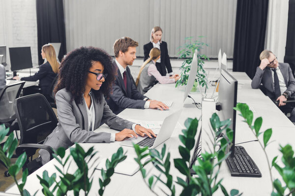 professional multiethnic young businesspeople working with digital devices in open space office 