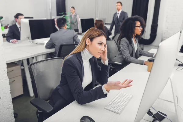 Stressed young businesswoman suffering from headache and looking at desktop computer in office — Stock Image Stressed Young Businesswoman Suffering Headache Looking Desktop Computer Office Stock Image
