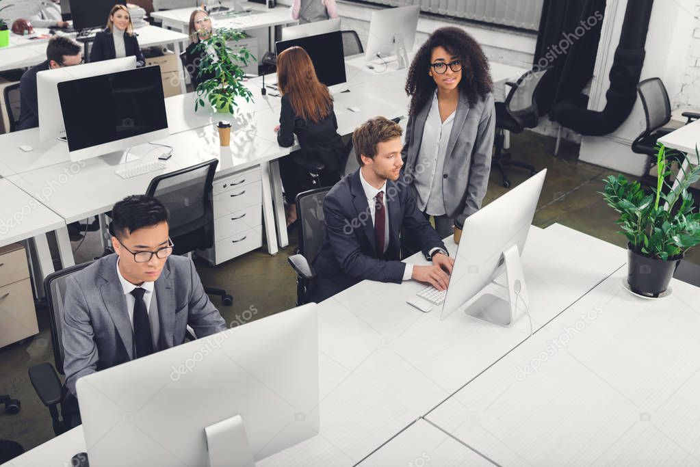high angle view of multiracial businesspeople using desktop computers in office 