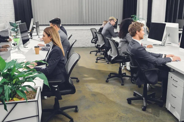 专业青年商人在正式服装工作与台式电脑在办公室的侧视图 — 图库照片