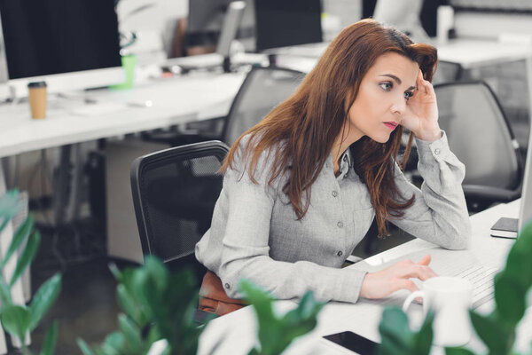 tired young businesswoman using desktop computer at workplace