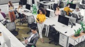 Blick aus der Vogelperspektive auf professionelle junge Geschäftsleute, die im Büro mit Computern und Papieren arbeiten  