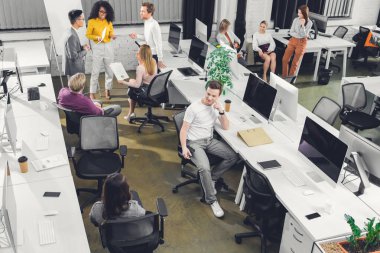 çalışma kağıtları ve açık alan ofisindeki bilgisayarlar ile profesyonel genç iş adamları yüksek açılı görünüş  