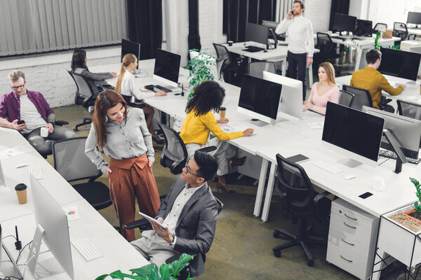 high angle view of young multiracial business colleagues working and talking in open space office 