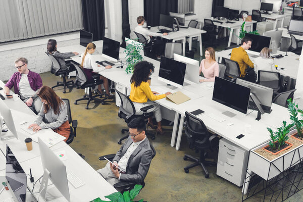 high angle view of young multiethnic businesspeople working in open space office