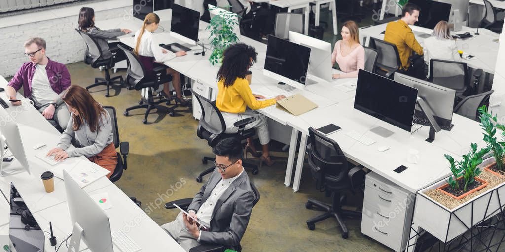 high angle view of professional multiethnic businesspeople working with digital devices in office