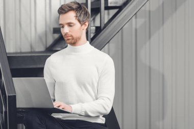 merdivenlerde oturan ve dizüstü bilgisayar kullanma office genç işadamı odaklı 
