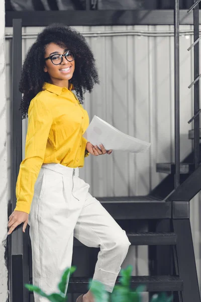 Atractiva Joven Mujer Negocios Afroamericana Sosteniendo Papeles Sonriendo Cámara Oficina — Foto de Stock