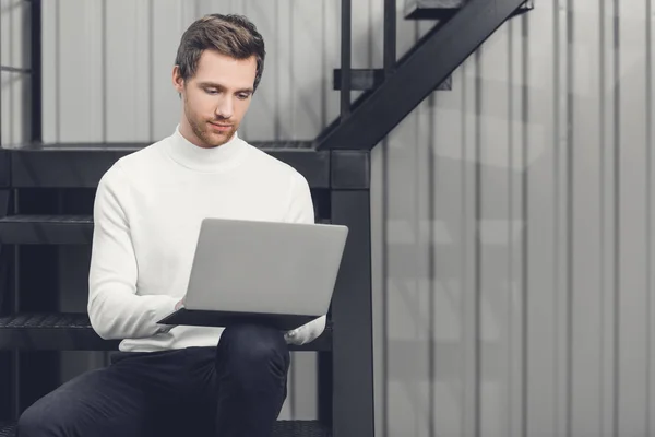 Schöner Lächelnder Junger Mann Sitzt Auf Der Treppe Und Benutzt — Stockfoto