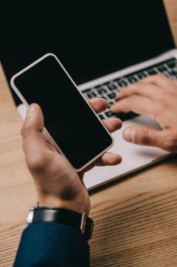 dizüstü bilgisayarda yazarken smartphone kullanarak işadamı kırpılmış görünümü  